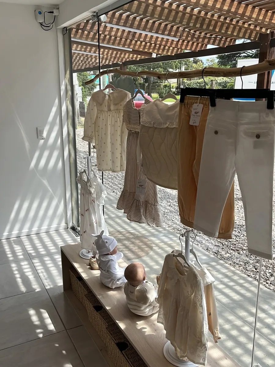 Vidriera de Tiny Nest con ropa de bebé colgada a la luz del sol